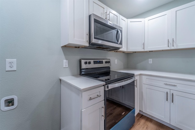 kitchen with light wood-style floors, light countertops, white cabinetry, and appliances with stainless steel finishes