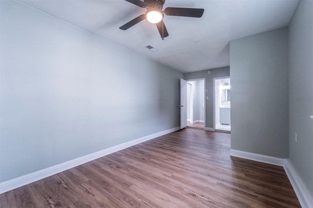 empty room with baseboards, ceiling fan, wood finished floors, and visible vents