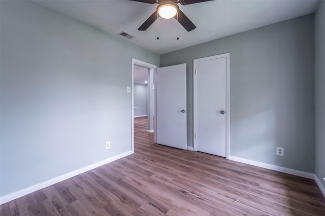 unfurnished bedroom with baseboards, ceiling fan, wood finished floors, and visible vents