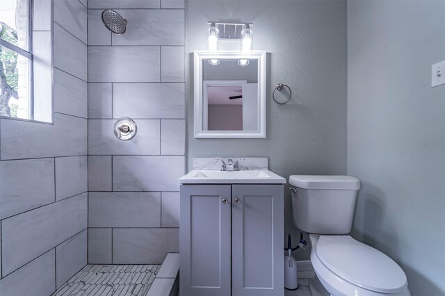 full bathroom with vanity, toilet, and tiled shower