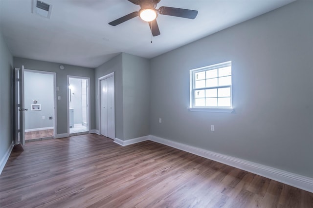 unfurnished room with baseboards, a ceiling fan, wood finished floors, and visible vents