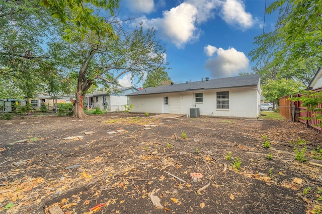 back of property with brick siding, central AC, and fence