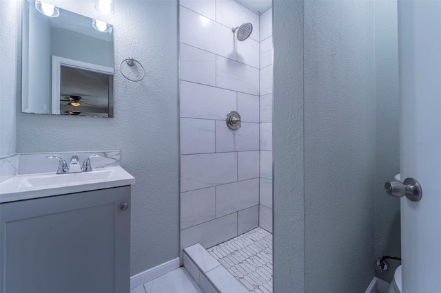 bathroom with vanity, a ceiling fan, and tiled shower
