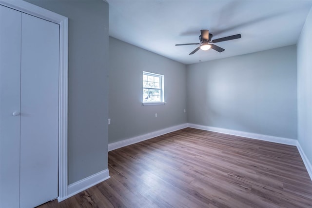 unfurnished bedroom featuring baseboards, a ceiling fan, wood finished floors, and a closet