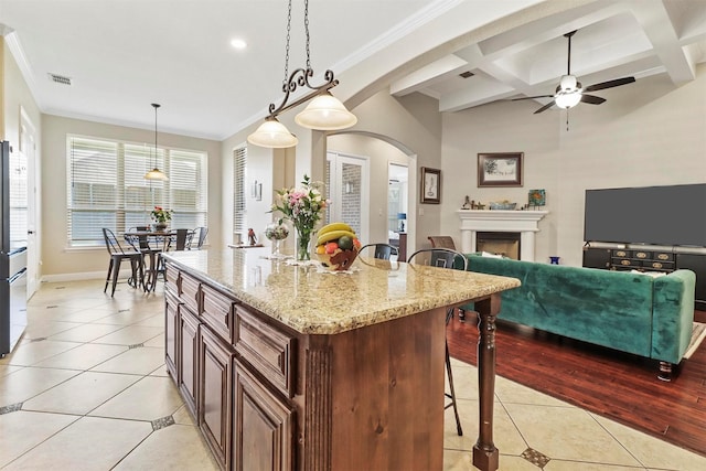 kitchen with visible vents, ceiling fan, a kitchen bar, coffered ceiling, and light tile patterned floors