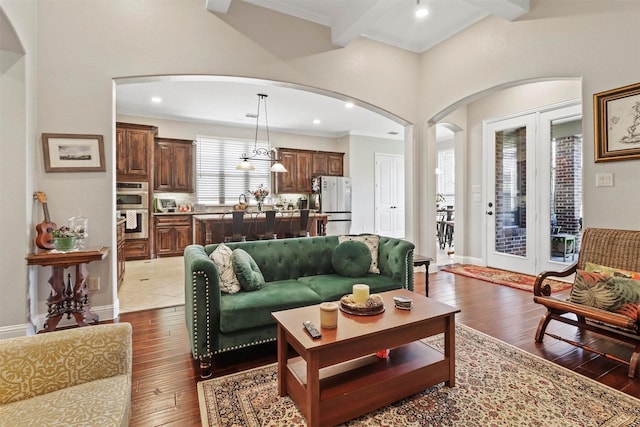 living room with wood-type flooring, arched walkways, crown molding, and french doors