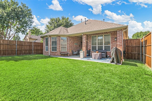 rear view of property with a lawn, brick siding, a fenced backyard, and a patio area