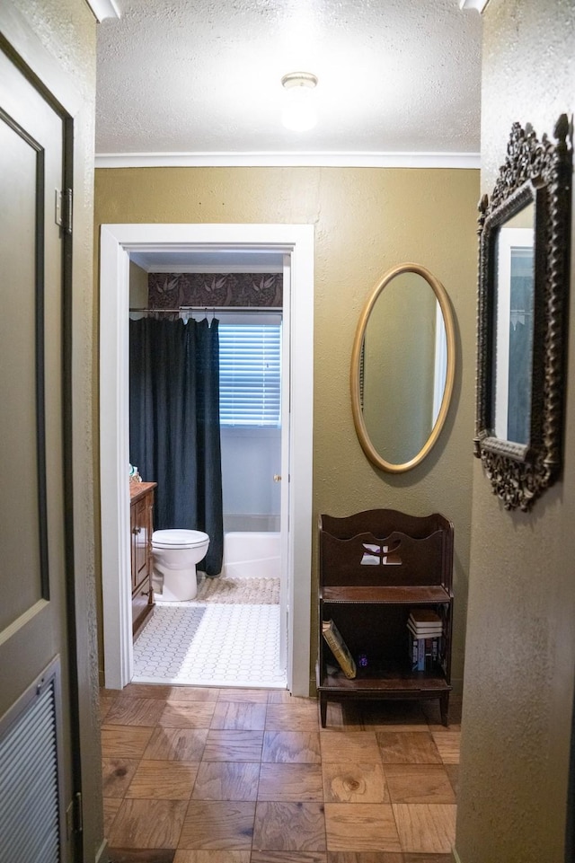corridor featuring ornamental molding and a textured ceiling