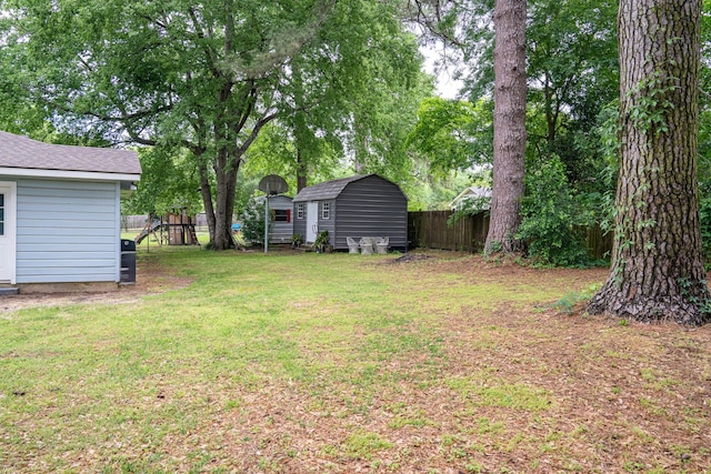 view of yard with fence, an outbuilding, and a shed