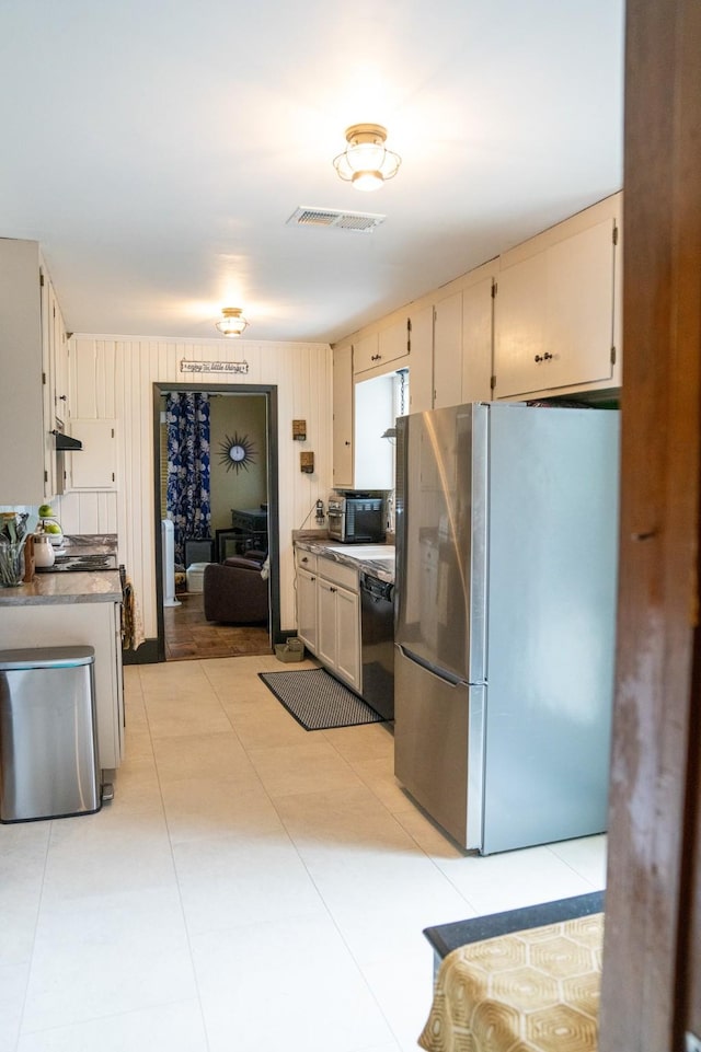 kitchen with visible vents, cream cabinets, range hood, freestanding refrigerator, and black dishwasher
