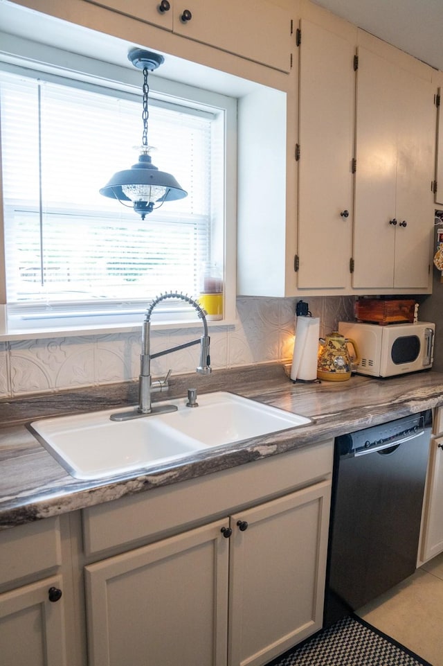 kitchen with a sink, white microwave, pendant lighting, and dishwasher