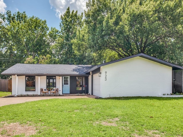 ranch-style house featuring a garage, fence, covered porch, and a front yard