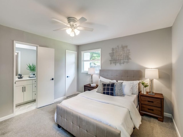 bedroom featuring baseboards, light colored carpet, a sink, and ensuite bathroom