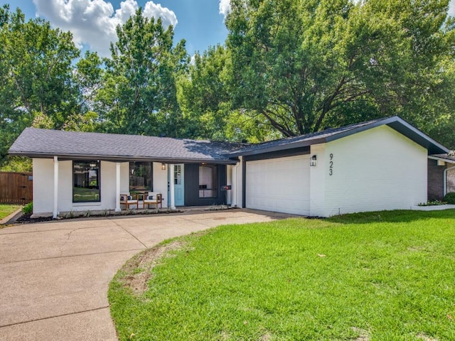 single story home with covered porch, a front yard, a garage, fence, and concrete driveway