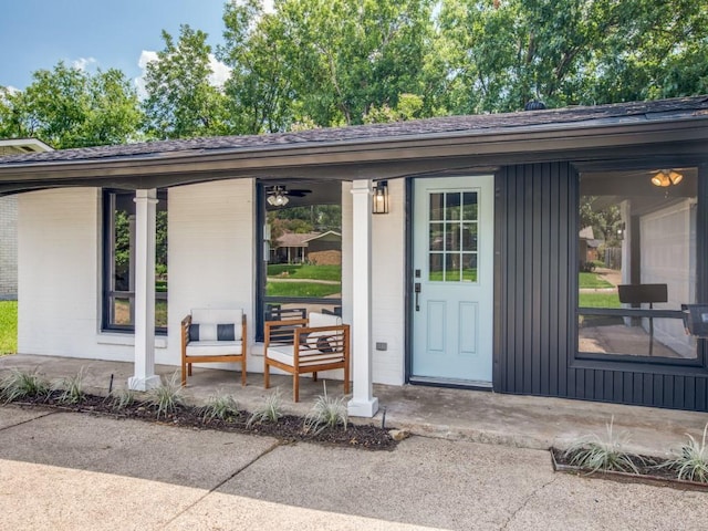 doorway to property featuring roof with shingles, covered porch, and board and batten siding