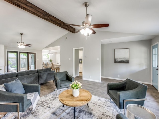 living area with a ceiling fan, lofted ceiling with beams, and wood finished floors
