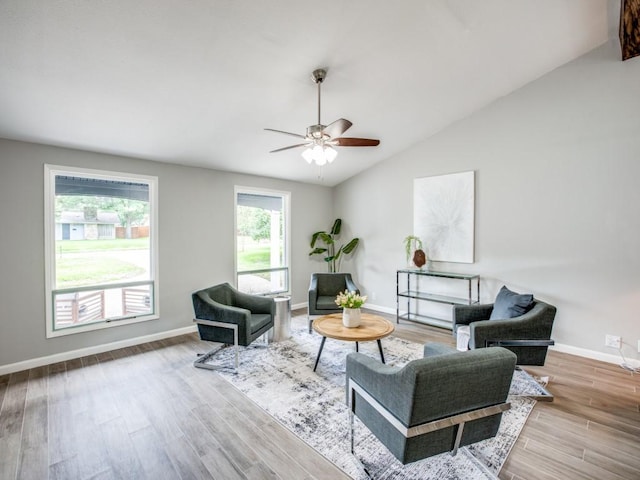living area featuring baseboards, a ceiling fan, vaulted ceiling, and wood finished floors