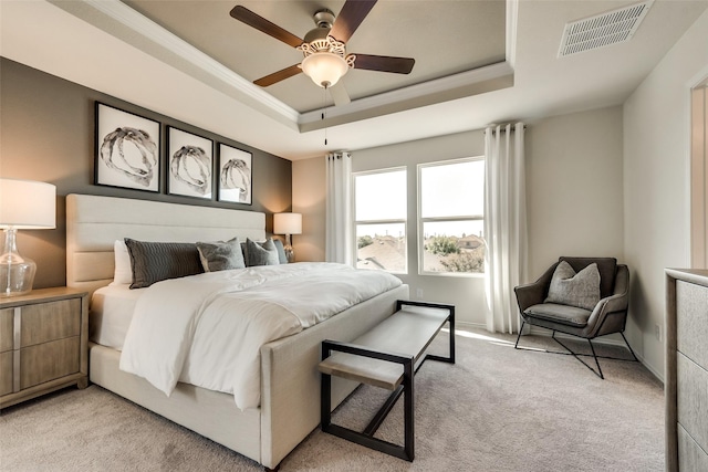 bedroom featuring visible vents, crown molding, light colored carpet, a raised ceiling, and a ceiling fan