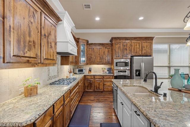 5916 River Highlands Dr, Mckinney, TX 75070 - kitchen with stainless steel appliances, a sink, brown cabinetry, crown molding, and light stone counters