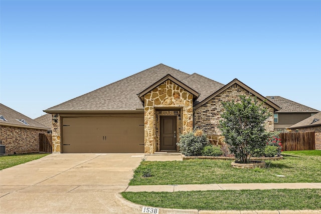 french country inspired facade featuring fence, a front lawn, concrete driveway, an attached garage, and stone siding