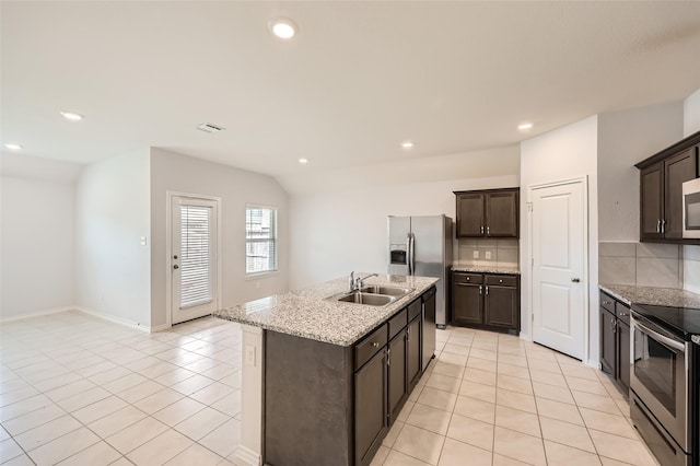 kitchen featuring dark brown cabinetry, tasteful backsplash, a sink, stainless steel appliances, and light tile patterned flooring