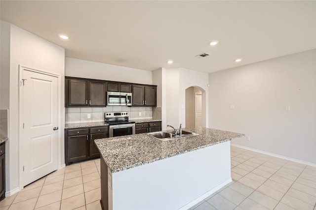 kitchen with a sink, appliances with stainless steel finishes, light tile patterned floors, and arched walkways