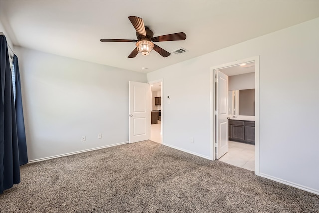 unfurnished bedroom featuring connected bathroom, light colored carpet, a ceiling fan, baseboards, and visible vents