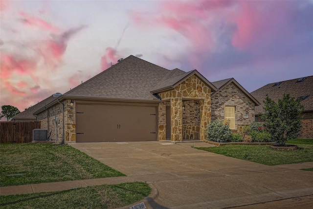 french provincial home with a garage, fence, a front yard, stone siding, and concrete driveway