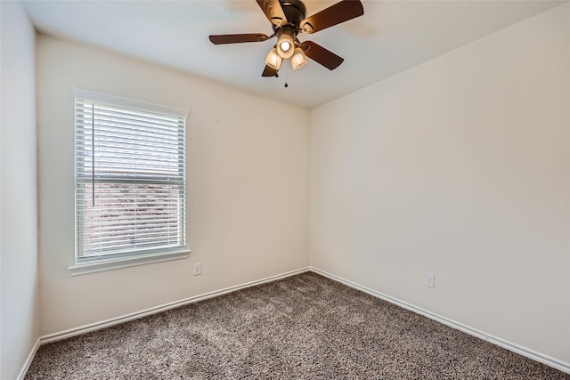 spare room featuring dark colored carpet, a ceiling fan, and baseboards