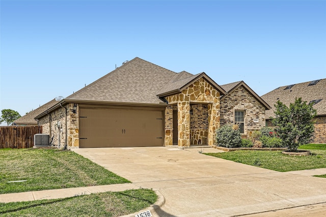 french country style house featuring fence, a front lawn, stone siding, a garage, and driveway