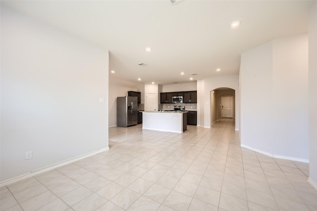unfurnished living room featuring arched walkways, baseboards, and recessed lighting