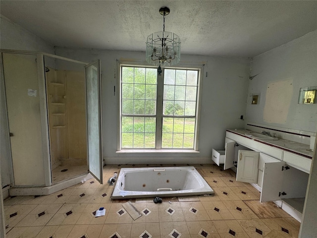 full bathroom with a textured ceiling, a tub with jets, an inviting chandelier, and a shower stall