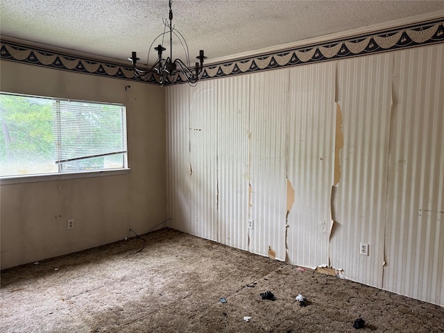 spare room with an inviting chandelier, a textured ceiling, and carpet