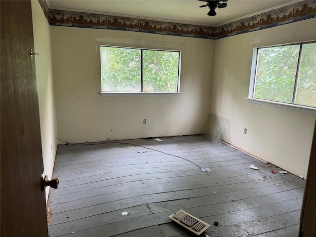unfurnished room with a healthy amount of sunlight, hardwood / wood-style flooring, and visible vents