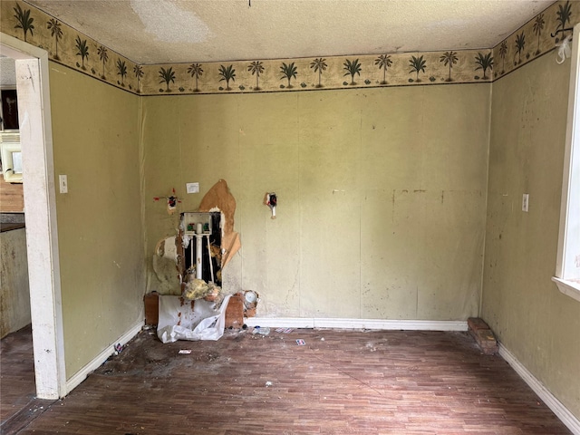 unfurnished room with baseboards, a textured ceiling, and wood finished floors