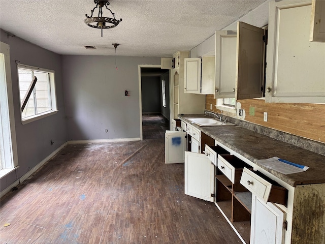 kitchen featuring a sink, dark wood finished floors, a textured ceiling, and visible vents