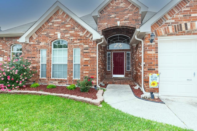 property entrance with a yard, brick siding, and a garage