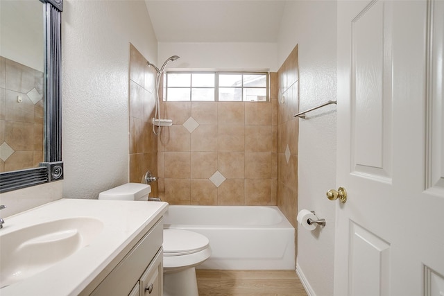 bathroom with shower / tub combination, wood finished floors, vanity, toilet, and a textured wall