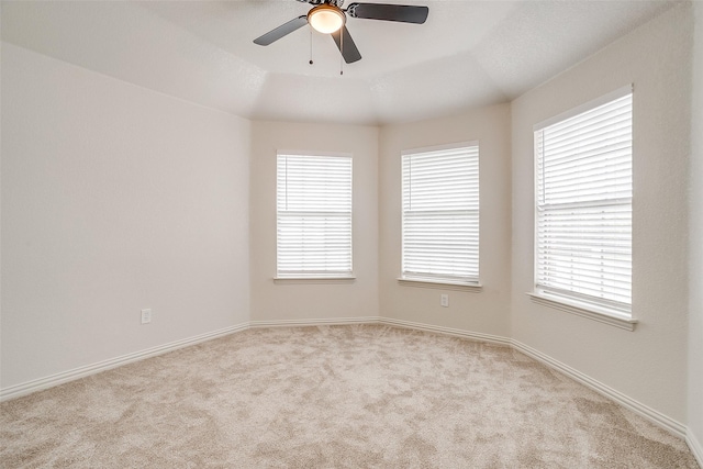 spare room featuring a healthy amount of sunlight, ceiling fan, and light colored carpet