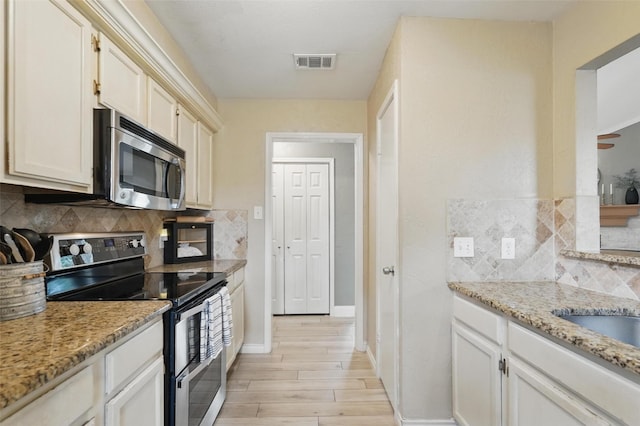 kitchen featuring visible vents, decorative backsplash, light wood finished floors, and stainless steel appliances