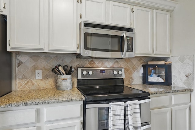 kitchen featuring white cabinets, appliances with stainless steel finishes, decorative backsplash, and light stone counters
