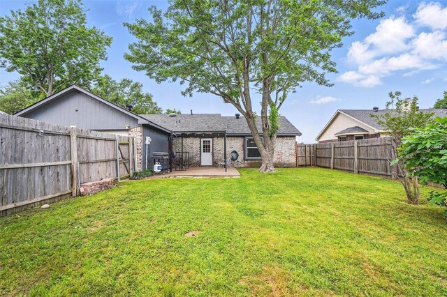 rear view of house with a patio, a fenced backyard, a lawn, and brick siding