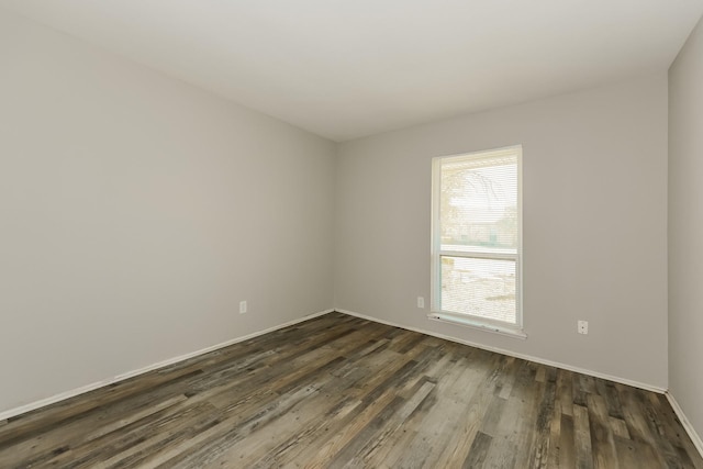 spare room featuring dark wood-style flooring and baseboards