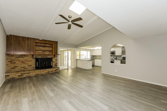 unfurnished living room featuring a ceiling fan, baseboards, a sink, and wood finished floors