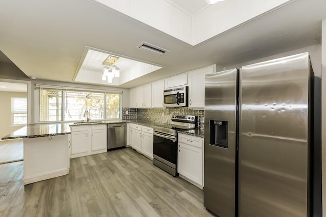 kitchen featuring a sink, dark stone counters, stainless steel appliances, white cabinetry, and visible vents