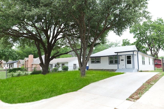 view of front of house with concrete driveway, fence, and a front lawn
