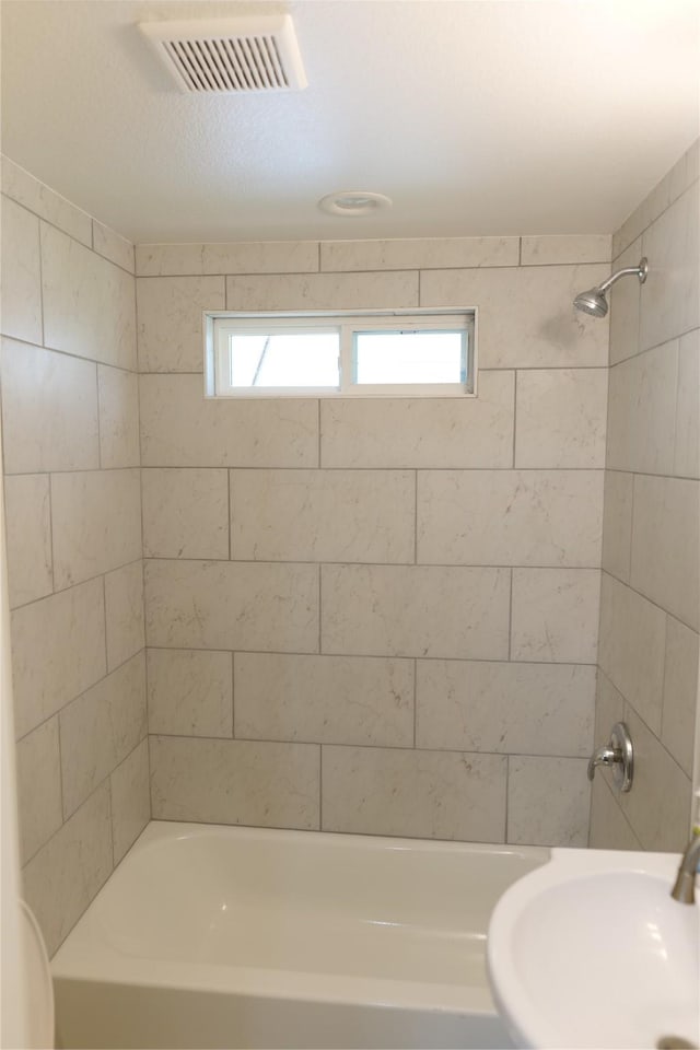 bathroom with visible vents, bathing tub / shower combination, a sink, and a wealth of natural light