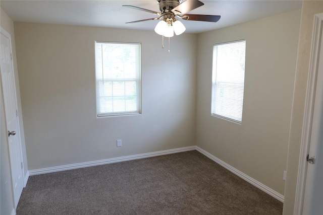 empty room featuring baseboards, a ceiling fan, dark colored carpet, and a wealth of natural light