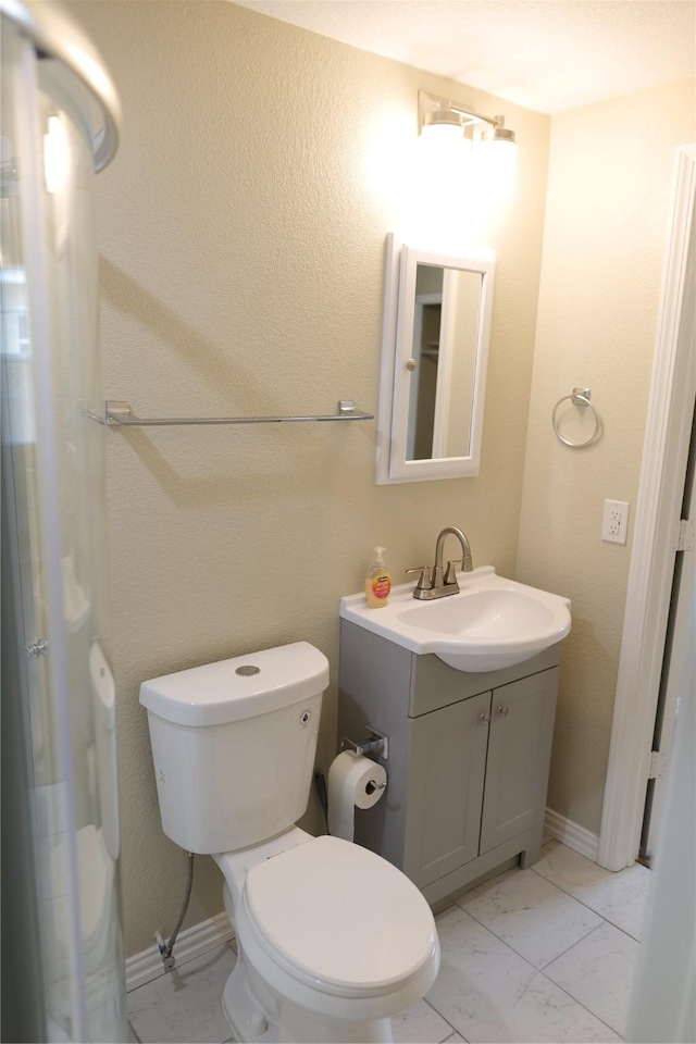 bathroom with toilet, baseboards, marble finish floor, and vanity