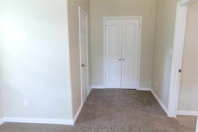unfurnished bedroom featuring carpet flooring, baseboards, and a closet